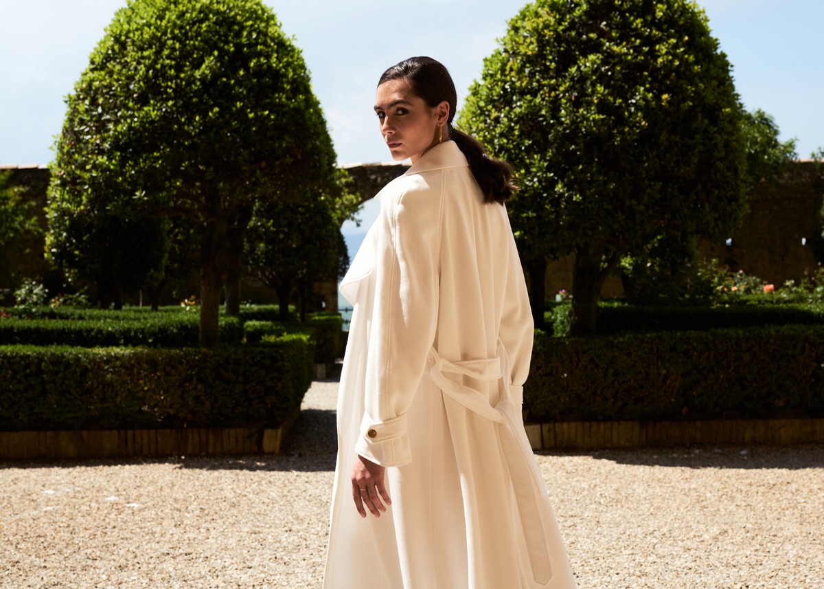 Trench bianco con bottoni gioiello ai polsi.
