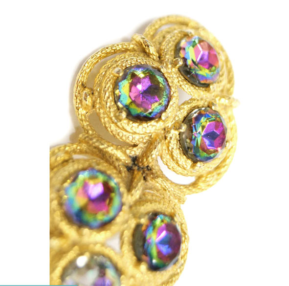 Elsa Schiaparelli, Spilla, anni ‘50. Iconica spilla con tre strass rotondi sfaccettati per lato, fiancheggiati da montature in Vermeil color oro simili a corde, che formano un grappolo triangolare su ciascun lato