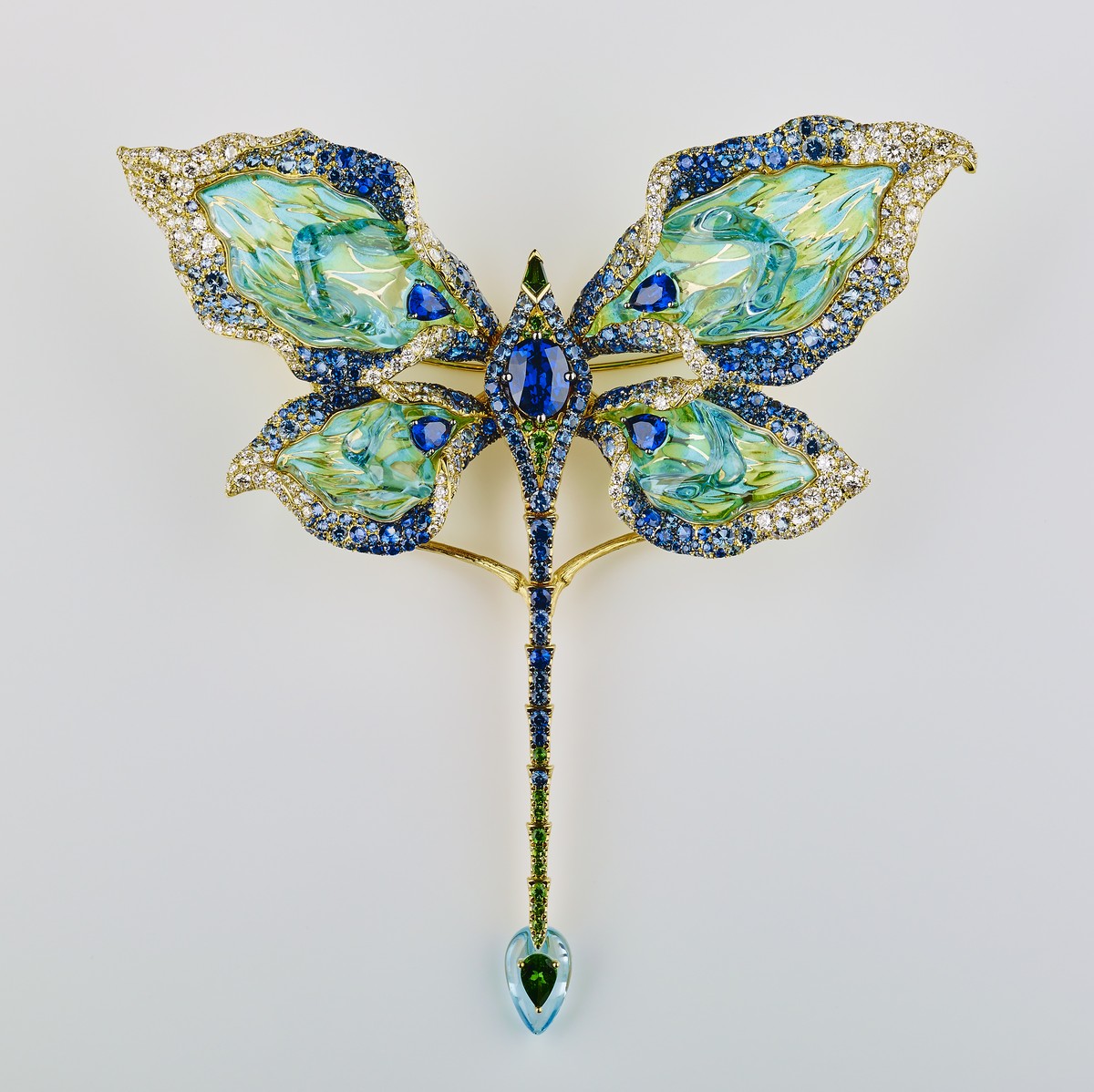 Spilla a forma di farfalla in smalto blu/verde con cristallo e topazio blu irregolare. Ali ispirate ai petali della calla che, premendo il pulsante in zaffiro al centro, si muoveranno su e giù