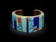 Sonwai per Hancocks London: un bracciale che unisce tradizione nativo americana Hopi e design contemporaneo Il bracciale rigido in oro giallo 18ct realizzato da Sonwai per Hancocks London. Un intarsio policromo unisce turchese, lapislazzuli, sugilite, conchiglia spiny oyster e rosarita
